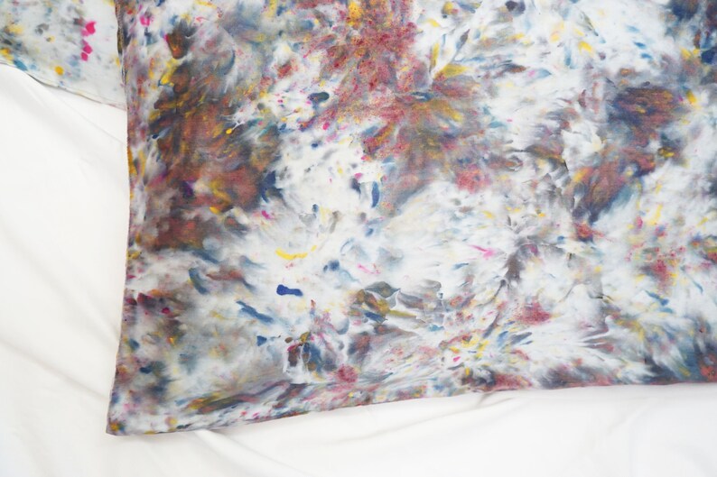 May include: A white pillowcase with a colorful tie-dye pattern in shades of blue, pink, yellow, and brown.
