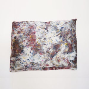 May include: A white pillowcase with a colorful abstract pattern in shades of blue, red, yellow, and brown. The pattern resembles a tie-dye design.