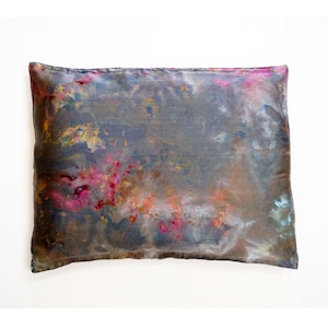 May include: A decorative pillow with a gray background and abstract patterns in shades of pink, orange, and blue.