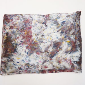 May include: A white pillowcase with a tie-dye pattern in shades of brown, blue, yellow, and pink.