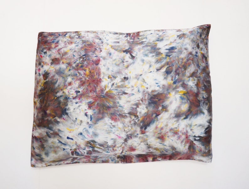 May include: A white pillowcase with a tie-dye pattern in shades of brown, blue, yellow, and pink.