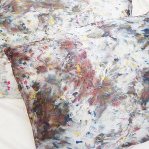May include: Two white pillowcases with a brown, blue, yellow, and pink abstract pattern.
