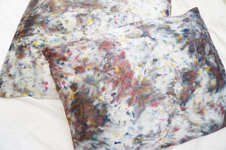 May include: Two white pillowcases with a brown, blue, yellow, and pink abstract pattern.