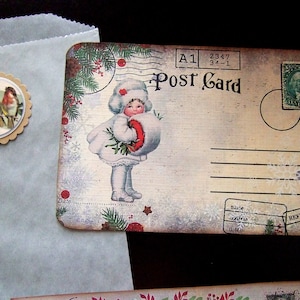 May include: Vintage postcard featuring a young girl in a white coat and hat holding a red and white bouquet. The postcard has a blue and white snowflake design and the text "Post Card" in black.