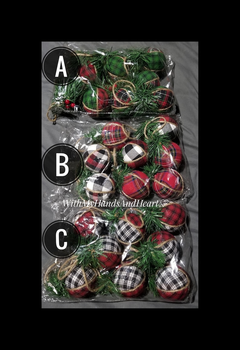 May include: Three clear plastic bags labeled A, B, and C, each containing multiple fabric-covered spherical ornaments. The ornaments feature red, green, black, and white plaid or buffalo check patterns, accented with green pine sprigs and twine.