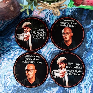 May include: Set of four round black coasters with orange trim, each featuring a different image of a man with glasses and text. The text includes phrases like "Coaster Motherfucker CAN YOU READ IT" and "Oh come on. Please don't fuck up my table."