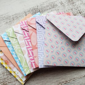 May include: A stack of colorful patterned envelopes with a variety of designs, including floral, geometric, and paisley patterns.