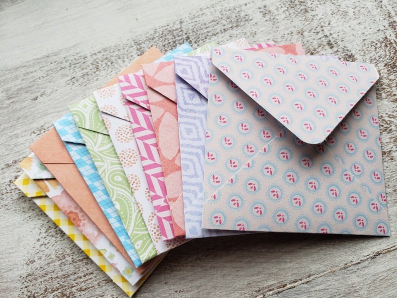 May include: A stack of colorful patterned envelopes with a variety of designs, including floral, geometric, and paisley patterns.