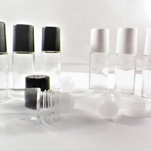 May include: A collection of clear glass roll-on bottles with black and white caps. Some bottles are standing upright, while others are lying down. The bottles are empty and ready to be filled with essential oils or other liquids.