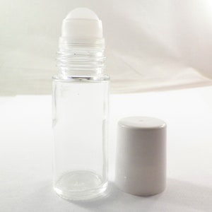 K&ouml;nnte beinhalten: Eine klare Glas-Rollflasche mit einem wei&szlig;en Kunststoff-Rollball und einem wei&szlig;en Kunststoffdeckel. Die Flasche ist leer.
