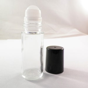 K&ouml;nnte beinhalten: Eine klare Glas-Rollflasche mit einem wei&szlig;en Rollball und einem schwarzen Plastikverschluss. Die Flasche ist leer.