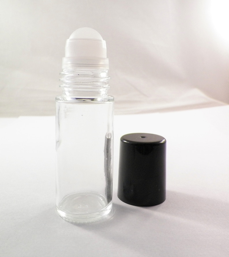 K&ouml;nnte beinhalten: Eine klare Glas-Rollflasche mit einem wei&szlig;en Rollball und einem schwarzen Plastikverschluss. Die Flasche ist leer.