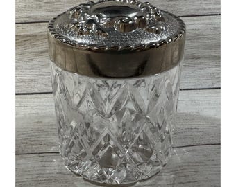 Tarro de tocador antiguo de cristal tallado grueso con tapa plateada ornamentada.