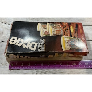 May include: A vintage Dixie Heritage Kitchen Cup Collection box. The box is black with white text and features images of the cups with various historical scenes. The box also includes a ruler with inch measurements.