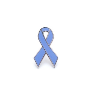 May include: A light blue ribbon pin with a silver-colored border. The pin is in the shape of a ribbon, commonly used as a symbol of awareness and support. The pin is set against a white background.