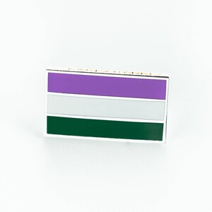 May include: A rectangular enamel pin displaying the genderqueer pride flag. The flag design features horizontal stripes of purple, white, and dark green, with a silver outline. The pin is set against a white background.