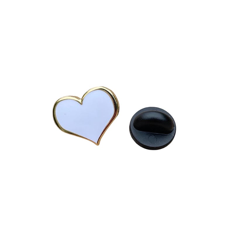 a white heart-shaped pin with a gold border, and a black pin with a gold-colored head.