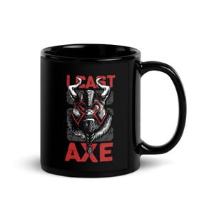 Peut inclure: Mug en céramique noire avec un motif de guerrier viking. L'illustration comprend un casque à cornes, une longue barbe et les mots "LEAST AXE" en rouge. La tasse a une grande anse.