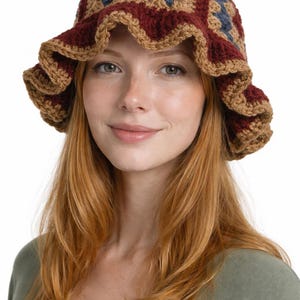 May include: A crocheted hat with a ruffled brim. The hat features a patchwork design in shades of burgundy, blue, and tan. The hat is a stylish accessory for any outfit.