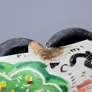May include: Close-up of a ceramic dish with a scalloped edge. The dish is decorated with a green, white, and black floral design. The edge of the dish is painted black.
