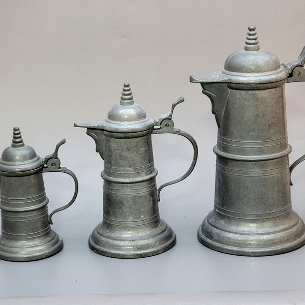 Three old German decorative pewter jugs in different sizes, marked as "Legally protected"