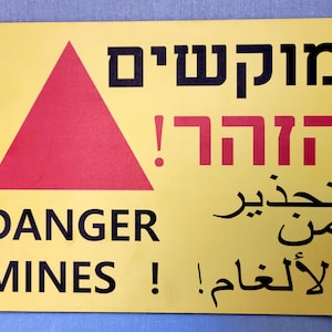 Vintage sign in three languages: English Hebrew and Arabic &quot;Danger Mines!&quot;