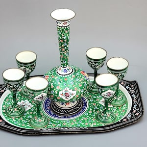 May include: A green and white enamelware serving set with a decorative floral design. The set includes a pitcher and six cups on a black tray.