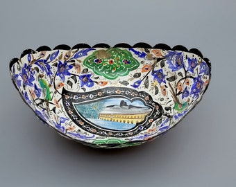 May include: A white ceramic bowl with a scalloped edge. The bowl is decorated with a colorful floral pattern and a scene of a building with arches. The bowl is a traditional design.