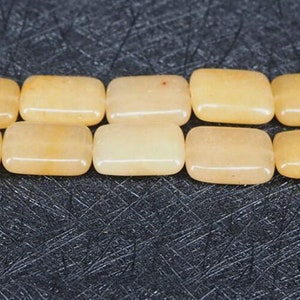 Puede incluir: Una hebra de cuentas de piedra preciosa rectangulares de color amarillo claro. Las cuentas son lisas y pulidas.