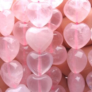 May include: A strand of pink heart-shaped gemstone beads. The beads are translucent and have a slight shimmer.