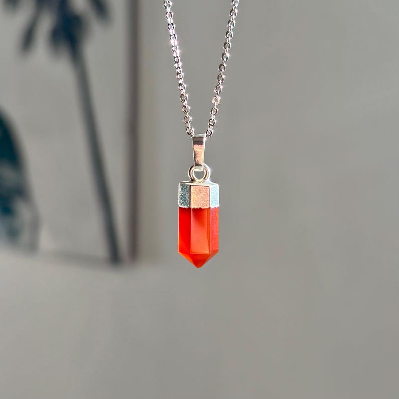 Pendentif en pierre rouge facettée avec monture argentée, suspendu à une chaîne fine en argent. Bijou en cornaline  minimaliste et élégant, idéal pour un style raffiné