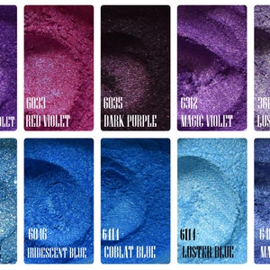 May include: A collection of shimmering cosmetic pigments in various shades of violet and blue. Each color is displayed in a rectangular container with a unique name and number, including "Violet," "Iridescent Violet," and "Sky Blue."
