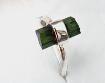 May include: A silver ring with a dark green gemstone set in a bezel setting.
