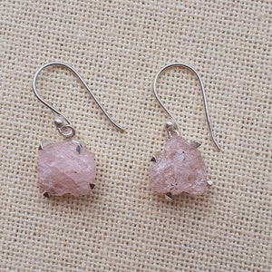 May include: A pair of silver earrings with pink, raw, crystal-shaped stones.