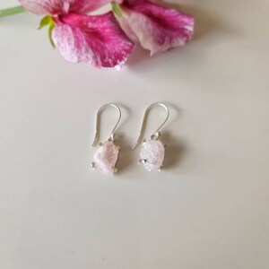 May include: A pair of silver earrings with pink, rough-cut gemstone drops.