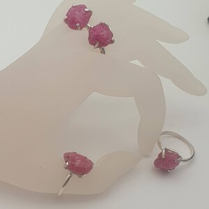 Peut inclure: Trois bagues en argent avec des pierres pr&eacute;cieuses roses brutes. Les bagues sont sur une main de mannequin blanche.