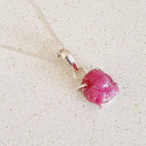 Peut inclure: Un collier en argent avec un pendentif en forme de rubis rose brut. Le rubis est serti dans une griffe en argent.