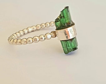 May include: A silver ring with a green tourmaline gemstone. The ring is made of small silver beads and the gemstone is set in a silver bezel.
