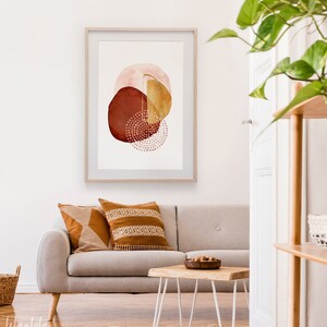 May include: A framed abstract watercolor painting with a gold, red, and pink color scheme. The painting features overlapping circles with a dotted pattern.