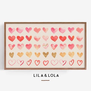 May include: A framed print with a watercolor design of pink and gold hearts. The print has the text "LILA & LOLA" at the bottom.