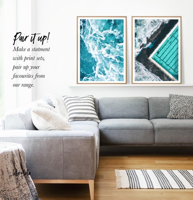 May include: Two framed prints of aerial ocean photography. The left print shows a turquoise ocean with white waves. The right print shows a turquoise pool with a white border, surrounded by turquoise water. The text "Pair it up! Make a statement with print sets, pair up your favourites from our range." is visible below the prints.