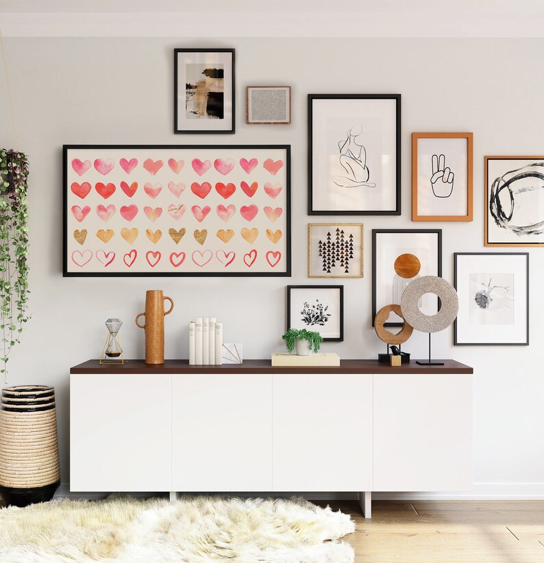 May include: A white cabinet with three doors and a dark brown countertop. The cabinet is decorated with a variety of framed artwork, including a print of hearts, a line drawing of a person, and a peace sign. There are also several decorative items on the countertop, including a vase, a hourglass, and a sculpture.