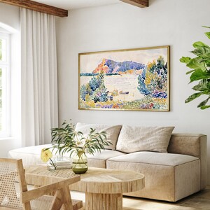 May include: A beige sectional sofa with two pillows sits in a living room with a wooden coffee table and a framed watercolor painting of a landscape with a lake and trees.