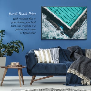 May include: A framed photograph of an aerial view of a Bondi Beach pool with turquoise water and white waves crashing against the shore. The text "Bondi Beach Print" is written in black text on a blue background.