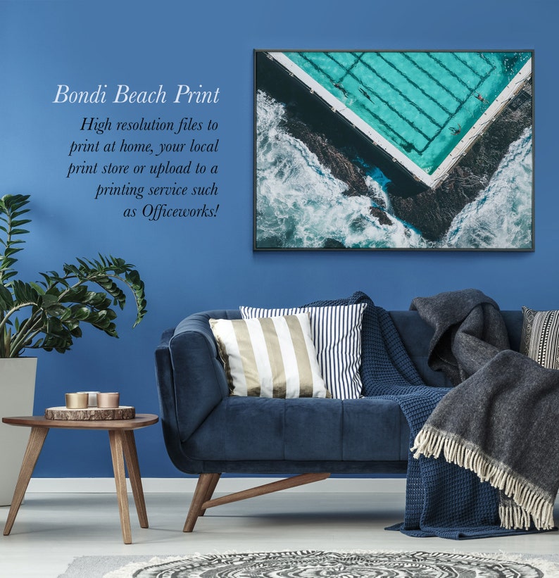 May include: A framed photograph of an aerial view of a Bondi Beach pool with turquoise water and white waves crashing against the shore. The text "Bondi Beach Print" is written in black text on a blue background.