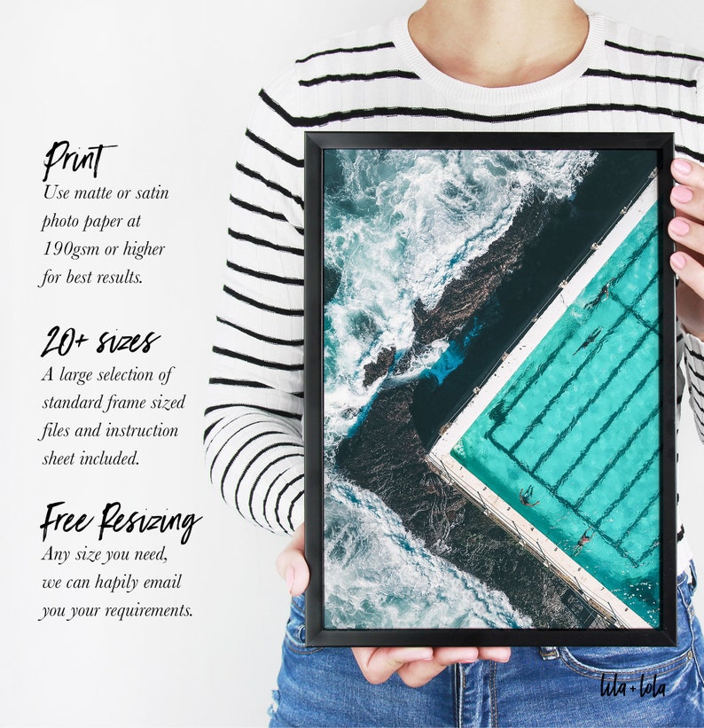 May include: An aerial view of a turquoise pool with swimmers, surrounded by dark rocks and white waves. The image is framed in a black frame with the text "lila-lola" in the bottom right corner.