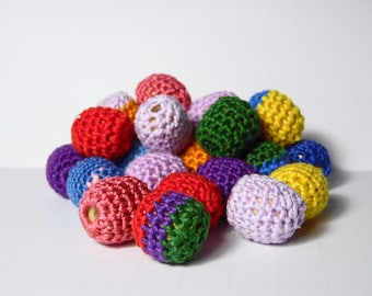 May include: A collection of colorful crocheted balls in various shades of red, pink, purple, blue, green, and yellow. The balls are made of soft yarn and have a textured surface.