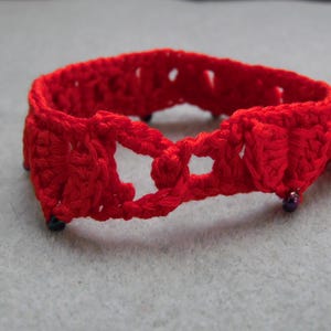 May include: Red crocheted bracelet with purple beads.