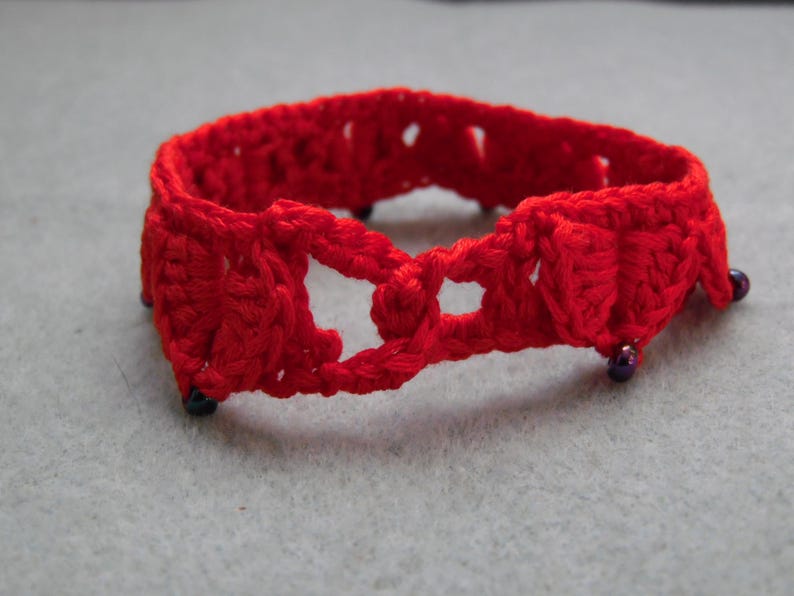 May include: Red crocheted bracelet with purple beads.