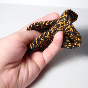 May include: A black and orange crocheted headband with a textured pattern.